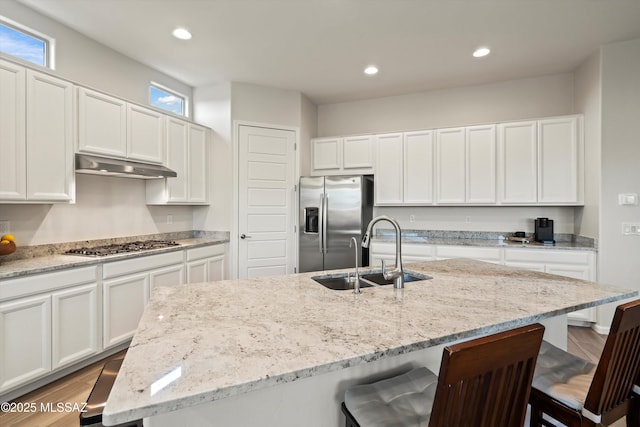 7797 S Indian Wheat Way, Tucson, AZ 85747 - kitchen with stainless steel appliances, under cabinet range hood, a sink, a kitchen bar, and light wood finished floors
