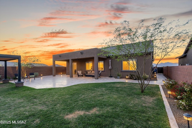 back of property at dusk with a patio area, stucco siding, an outdoor living space, a fenced backyard, and a lawn