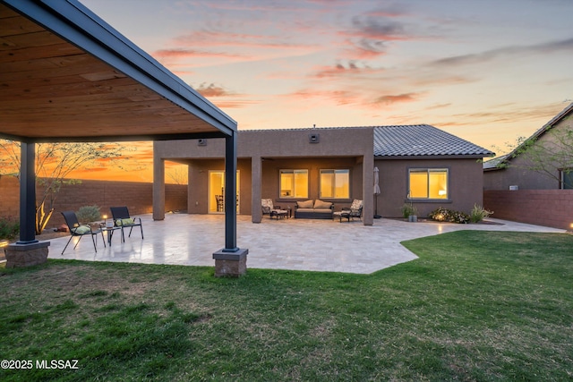 rear view of house with a patio, stucco siding, a fenced backyard, a yard, and an outdoor living space