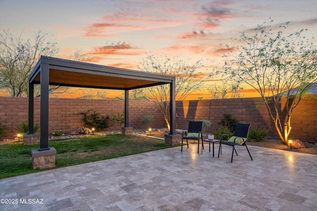 patio terrace at dusk featuring a lawn and a fenced backyard