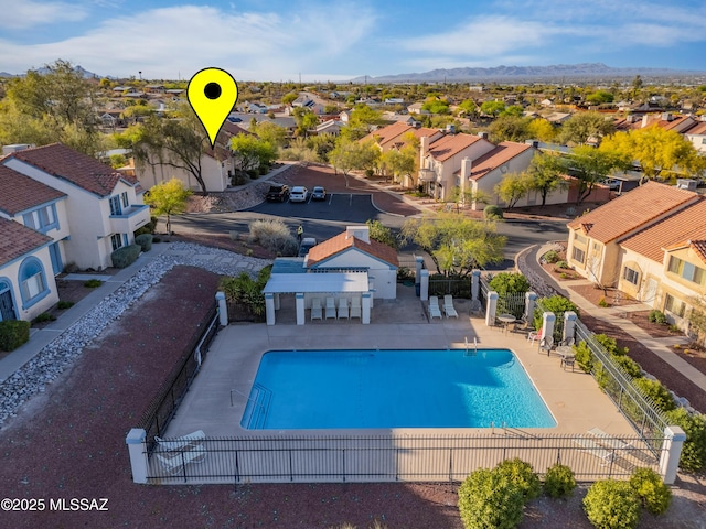 community pool with a patio, a mountain view, fence, and a residential view
