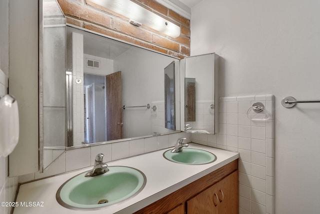 bathroom with double vanity, visible vents, tile walls, and a sink