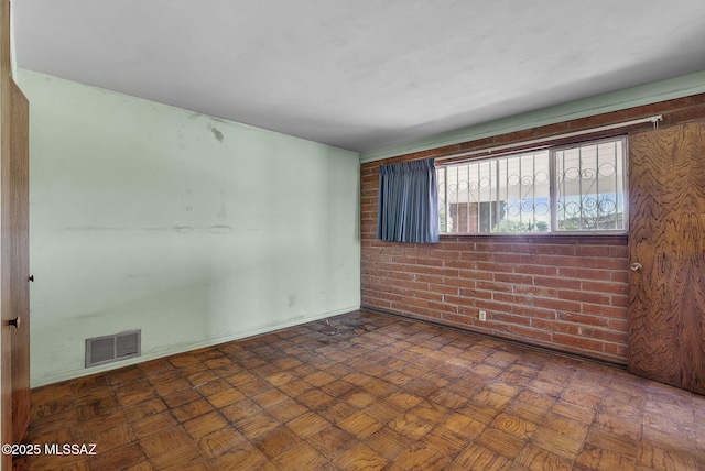 spare room featuring brick wall and visible vents