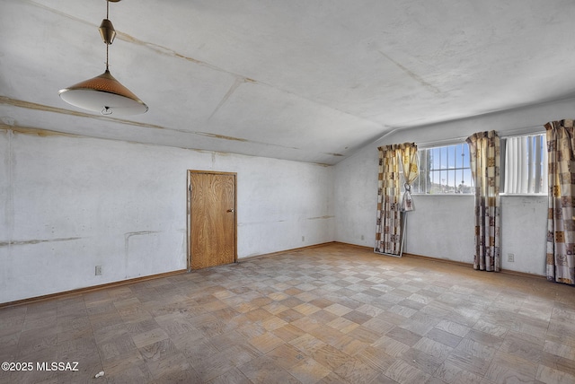 empty room featuring baseboards and vaulted ceiling