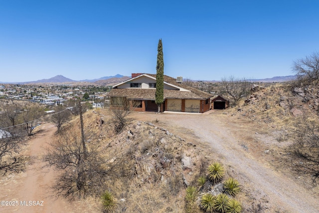 view of front of house with a garage, a mountain view, and dirt driveway