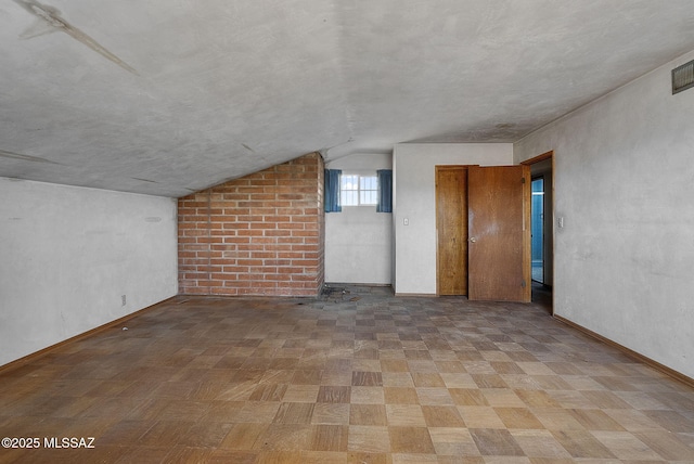 spare room featuring baseboards and vaulted ceiling