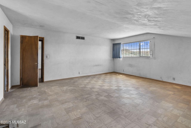 spare room featuring tile patterned floors, baseboards, lofted ceiling, and visible vents