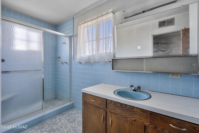 bathroom featuring a shower stall, vanity, visible vents, and backsplash