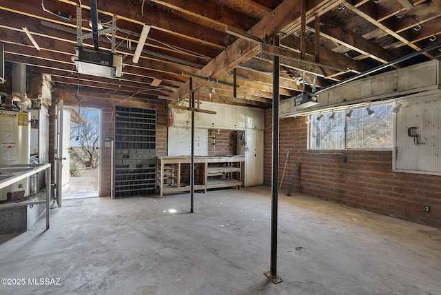 below grade area with brick wall, gas water heater, and plenty of natural light