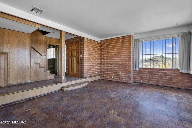empty room featuring visible vents, brick wall, and stairs