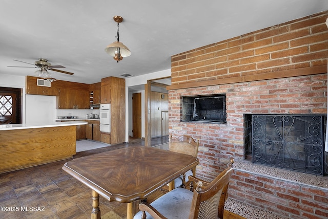 dining room with visible vents, a ceiling fan, and a brick fireplace