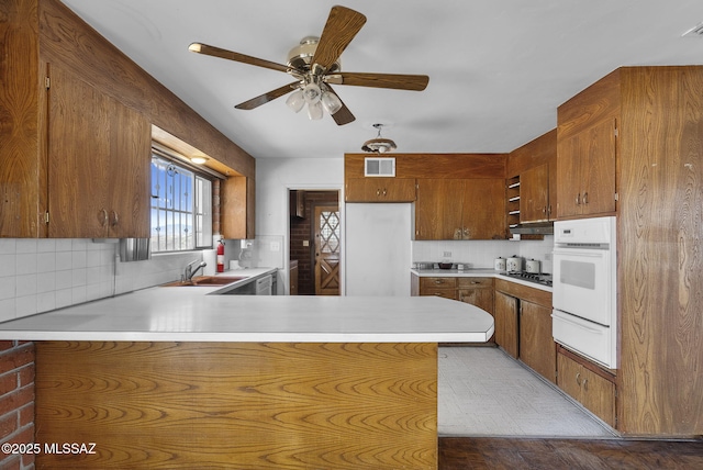 kitchen with white oven, visible vents, light countertops, a peninsula, and a warming drawer