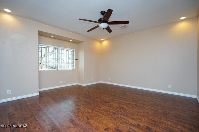 empty room featuring dark wood-style flooring, baseboards, a ceiling fan, and visible vents