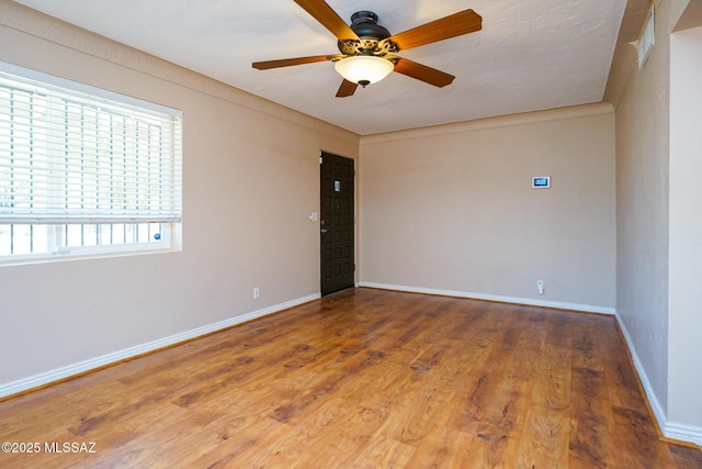 empty room with wood finished floors, ceiling fan, and baseboards