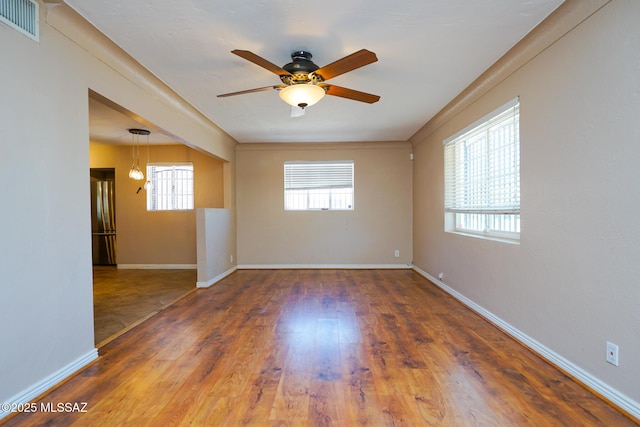 spare room featuring visible vents, ceiling fan, plenty of natural light, and wood finished floors