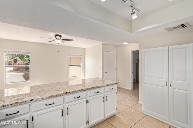 kitchen with light tile patterned floors, ceiling fan, visible vents, light stone counters, and white cabinets