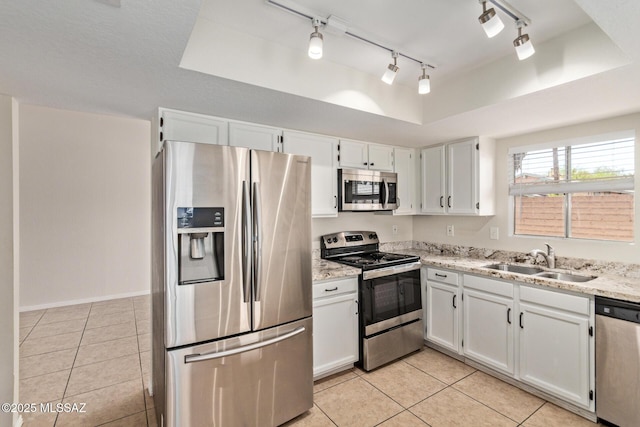 kitchen with a raised ceiling, light tile patterned flooring, a sink, and stainless steel appliances