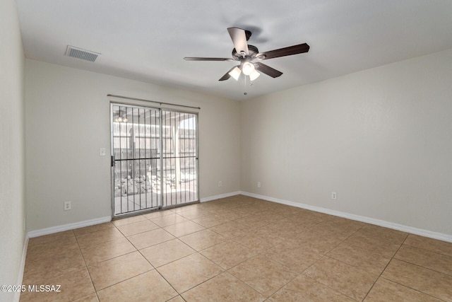spare room featuring light tile patterned flooring, visible vents, a ceiling fan, and baseboards