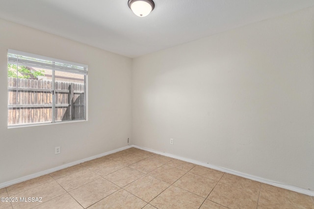 empty room featuring light tile patterned flooring and baseboards