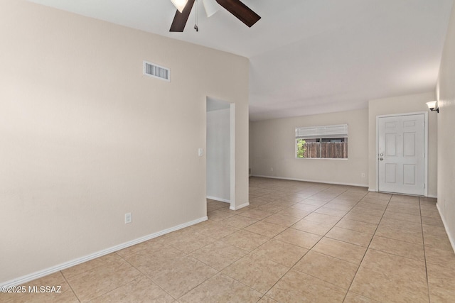 empty room with light tile patterned floors, visible vents, ceiling fan, and baseboards