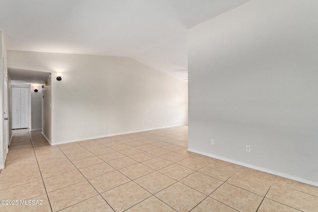 spare room featuring light tile patterned floors, lofted ceiling, and baseboards