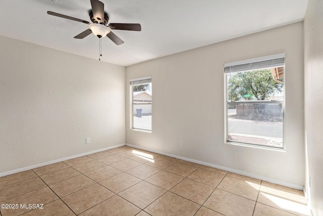 spare room with light tile patterned floors, a wealth of natural light, and ceiling fan