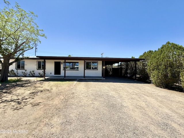 view of front of property with dirt driveway and an attached carport