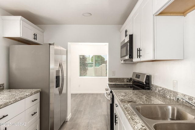 407 E 35th St, Tucson, AZ 85713 - kitchen with light stone counters, stainless steel appliances, a sink, light wood-style floors, and white cabinetry