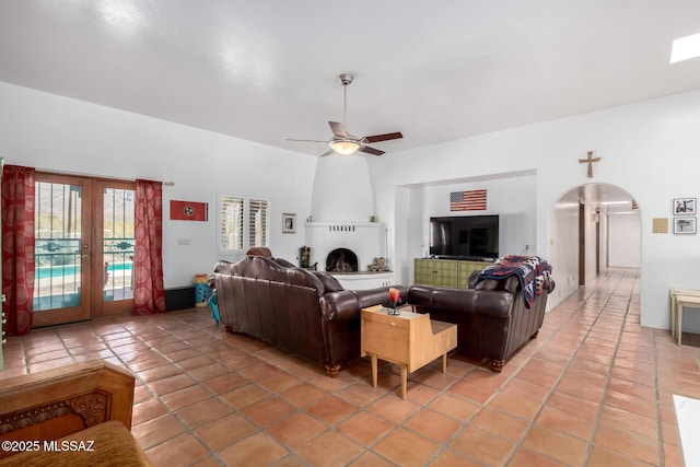 living room with arched walkways, light tile patterned floors, and a ceiling fan