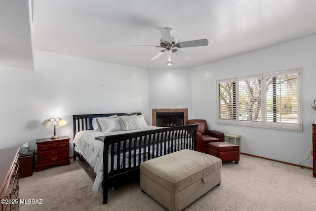 carpeted bedroom with baseboards, ceiling fan, and a fireplace
