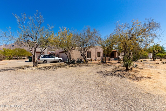 pueblo-style home featuring a garage, driveway, and stucco siding