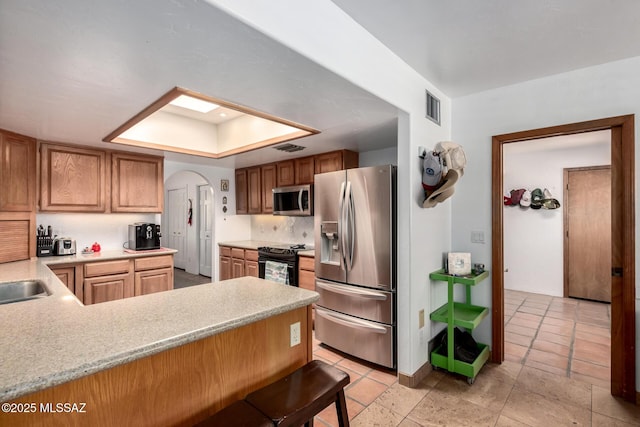 kitchen featuring a peninsula, light countertops, visible vents, a tray ceiling, and appliances with stainless steel finishes