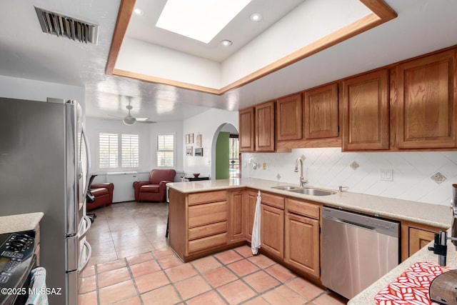 kitchen with visible vents, a tray ceiling, stainless steel appliances, arched walkways, and a sink