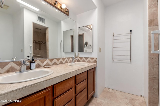 bathroom with a sink, visible vents, tasteful backsplash, and double vanity