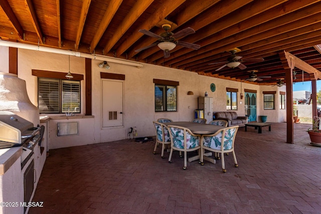 view of patio featuring a grill, outdoor dining space, a ceiling fan, and an outdoor kitchen