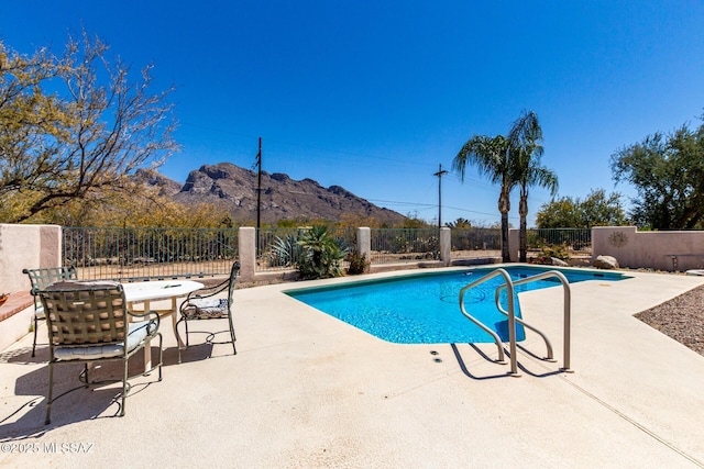 view of swimming pool featuring a mountain view, a patio area, a fenced in pool, and fence