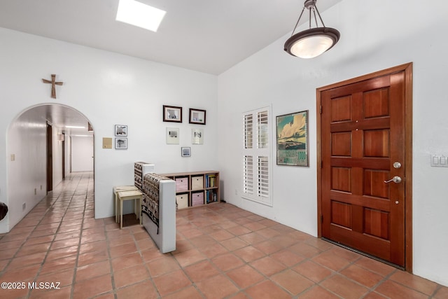 foyer entrance with light tile patterned floors and arched walkways