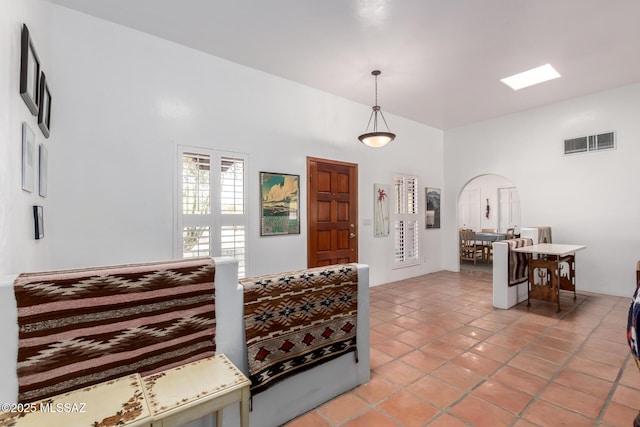 foyer entrance featuring arched walkways, light tile patterned flooring, a towering ceiling, and visible vents