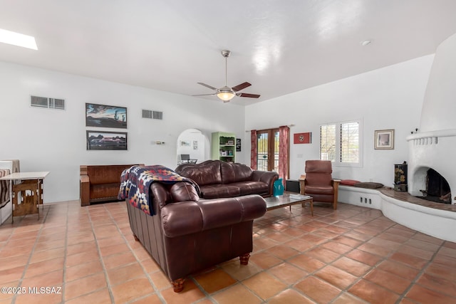 living area with visible vents, a large fireplace, light tile patterned flooring, and ceiling fan