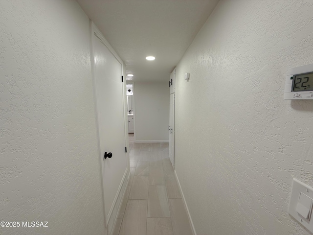 corridor with a textured wall and baseboards