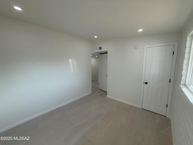spare room featuring baseboards, visible vents, and recessed lighting