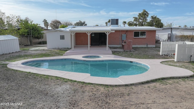 rear view of house featuring central AC, an outdoor hot tub, fence, a patio, and brick siding