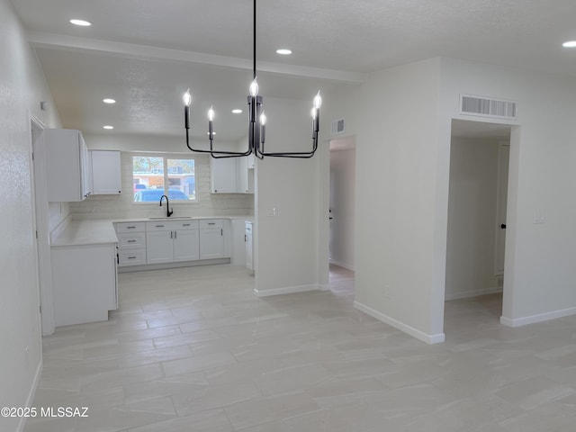 kitchen featuring an inviting chandelier, visible vents, light countertops, a sink, and decorative backsplash