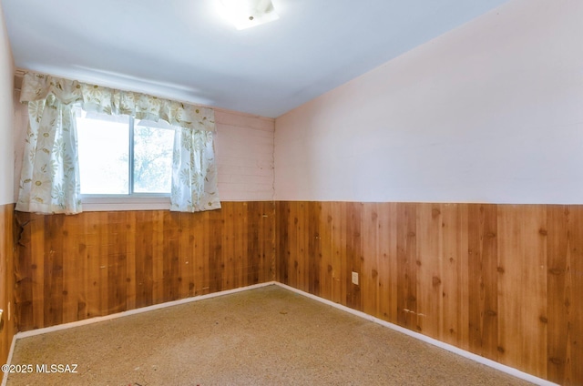 spare room with wood walls and wainscoting