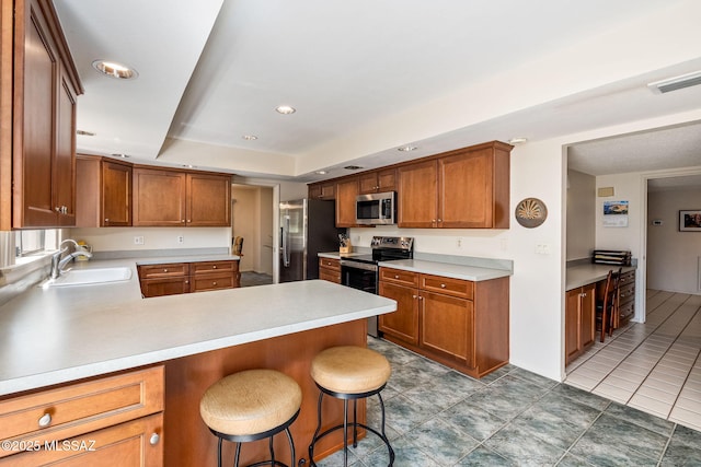 kitchen with light countertops, visible vents, a tray ceiling, stainless steel appliances, and a sink
