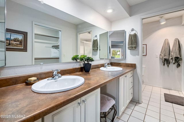 bathroom featuring a shower with shower door, tile patterned floors, double vanity, and a sink