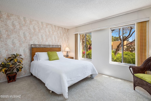bedroom featuring a textured ceiling, wallpapered walls, and carpet flooring