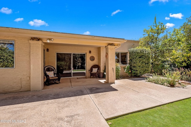 rear view of house featuring a patio area and stucco siding