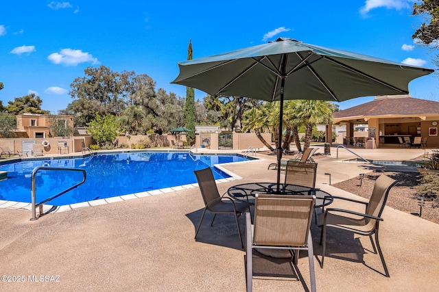 community pool with a patio and fence