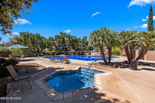 community pool with a patio and a hot tub